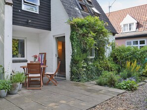 Une maison avec un patio, une table et des chaises.