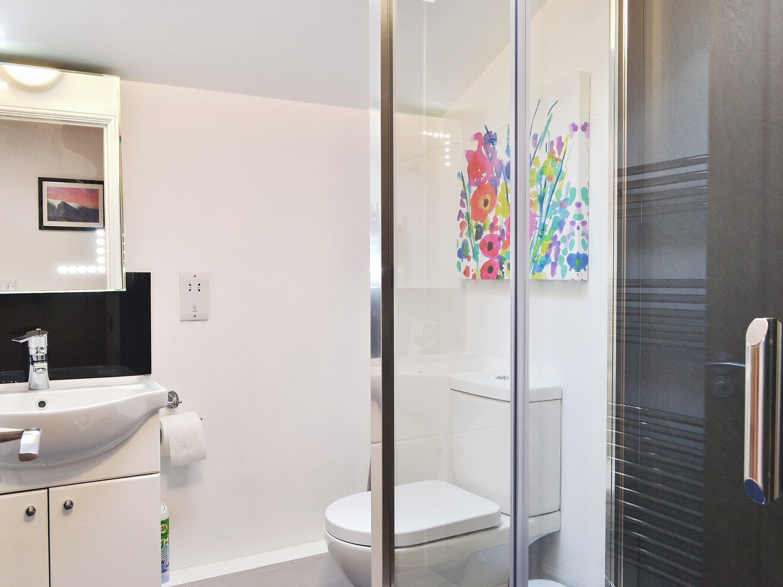 A modern bathroom with a white sink, toilet, and shower area.