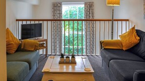 A living room with a TV, two sofas, a coffee table, and a window with curtains. - County House Apartment - 27911 (York)