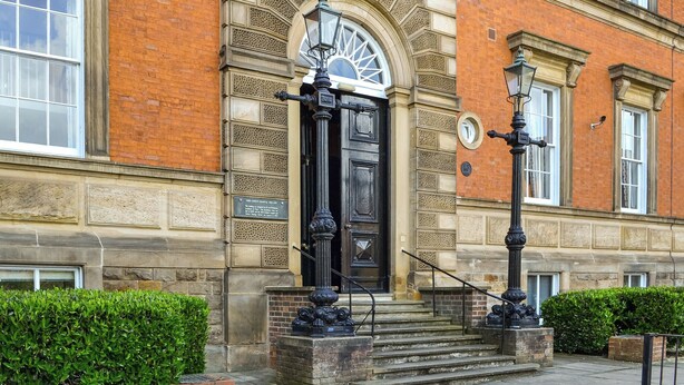 A historic building with a prominent entrance, a large arched doorway, and a decorative stone facade. - County House Apartment - 27911 (York)