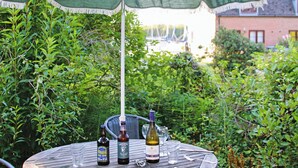 A round table with a green and white umbrella, two bottles of beer, and a wine bottle. - 2 bedroom accommodation in Island Harbour, near Newport (Island Harbour, near Newport)