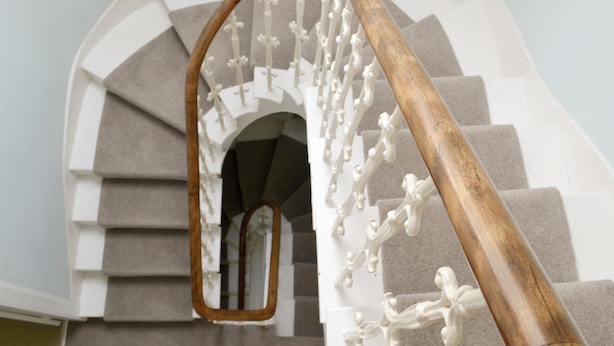 Un escalier avec une rampe en bois et un miroir qui reflète les marches.