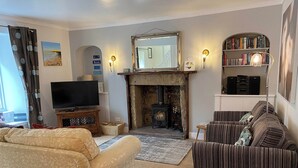 Una sala de estar con chimenea, televisor, estantería y sofá.