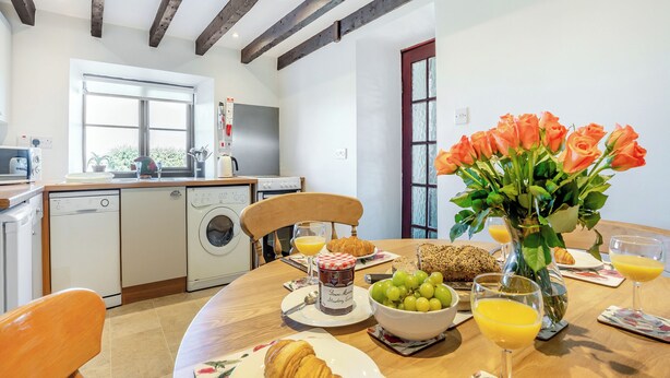 Une cuisine équipée d’un lave-linge, d’une table à manger dressée avec de la nourriture et des boissons, et d’une fenêtre donnant sur un beau paysage.