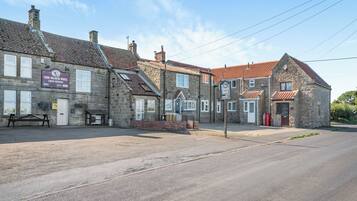 A stone building with a sign for 'The Black Bull Free House' and a bench outside.