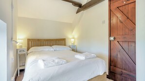 Une chambre à coucher avec un lit en bois, des lampes de chevet, une porte en bois et un mur blanc.