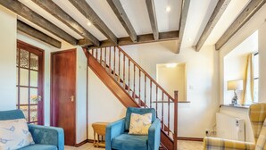 Un salon avec un escalier en bois, deux canapés, une petite table et un radiateur.