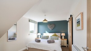 A bedroom with a bed, bedside tables, a mirror, a radiator, and a window.