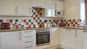 A modern kitchen with white cabinets, a microwave, a toaster, and a wooden countertop.