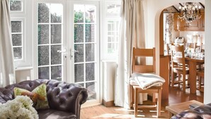 A living room with a leather sofa, a wooden chair, a dining table, and a chandelier. - 3 bedroom accommodation in Winterton-on-Sea, near Great Yarmouth (Winterton-on-Sea, near Great Yarmouth)