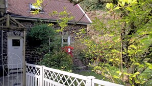 Un bâtiment en pierre avec un toit recouvert de tuiles rouges, une clôture blanche et une enseigne sur laquelle on peut lire « HEALE COTTAGE ».