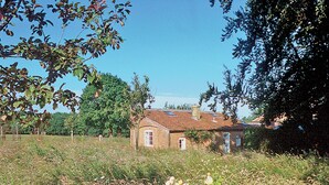 Ein rustikales Haus mit Ziegelaußenwand, einem Ziegeldach und einer kleinen Veranda.