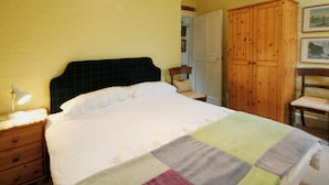 Ein Schlafzimmer mit einem Bett, einem Holzschrank, einem Stuhl und einem Nachttisch mit Lampe.
