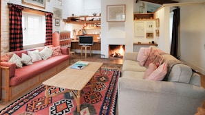 Ein gemütliches Wohnzimmer mit Kamin, einer Couch, einem Fernseher und einem Essbereich.