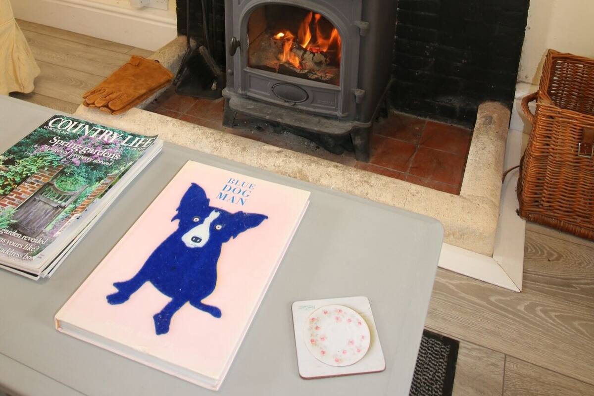 Una sala de estar con chimenea, una mesa con revistas y un libro, y un espejo sobre la chimenea.