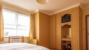 Un dormitorio con una cama grande, un escritorio y un televisor montado encima.