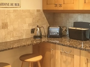 A kitchen with a granite countertop, a kettle, a toaster, and wooden cabinets.