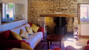 Ein gemütliches Wohnzimmer mit Steinwand, Kamin, einer Couch mit Kissen und einem Couchtisch.