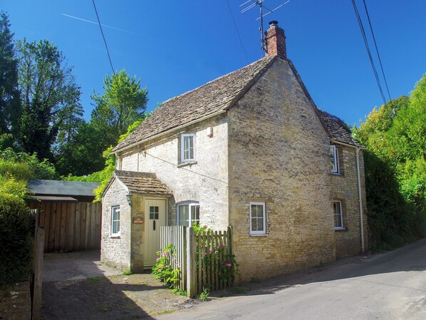 A stone cottage with a sloped roof, a chimney, and a wooden gate. - 1 bedroom accommodation in Chedworth, near Cheltenham (Chedworth, near Cheltenham)