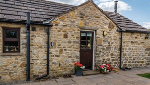 A stone building with a sloped roof, a wooden door, and a window with shutters. - 1 bedroom accommodation in near Middleham, Leyburn (near Middleham, Leyburn)