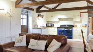 A cozy living room with a brown leather sofa, a dining table with a checkered tablecloth, and a kitchen with white cabinets and a blue stove. - 1 bedroom accommodation in near Middleham, Leyburn (near Middleham, Leyburn)