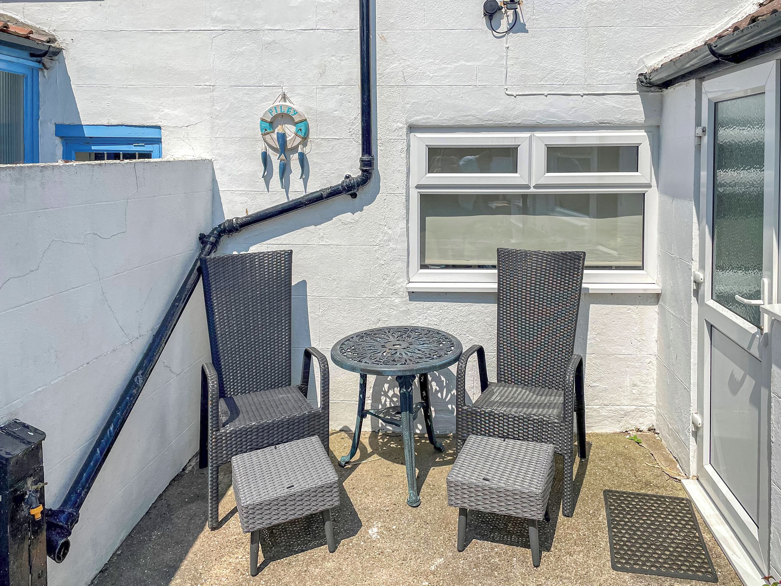 A small patio area with wicker furniture, a round table, and a window.