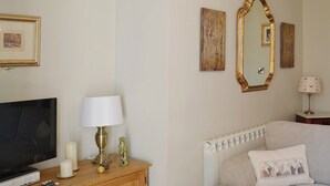 A living room with a television, wooden cabinet, and a beige sofa. - 2 bedroom accommodation in Whitby (Whitby)