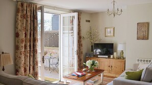 A living room with a sofa, a coffee table, a television, and a cabinet. - 2 bedroom accommodation in Whitby (Whitby)