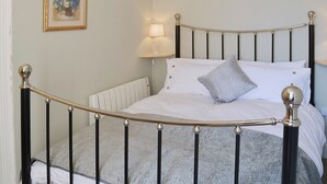 A neatly made bed with a metal frame, white bedding, and a decorative pillow. - 2 bedroom accommodation in Whitby (Whitby)