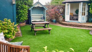 A well-maintained garden with a wooden bench, a small gazebo, and a stone wall. - 2 bedroom accommodation in Newton Reigny (Newton Reigny)