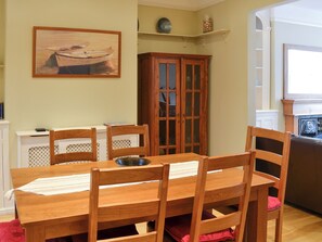Uma área de jantar com uma mesa e cadeiras de madeira, um armário com portas de vidro e um quadro na parede.