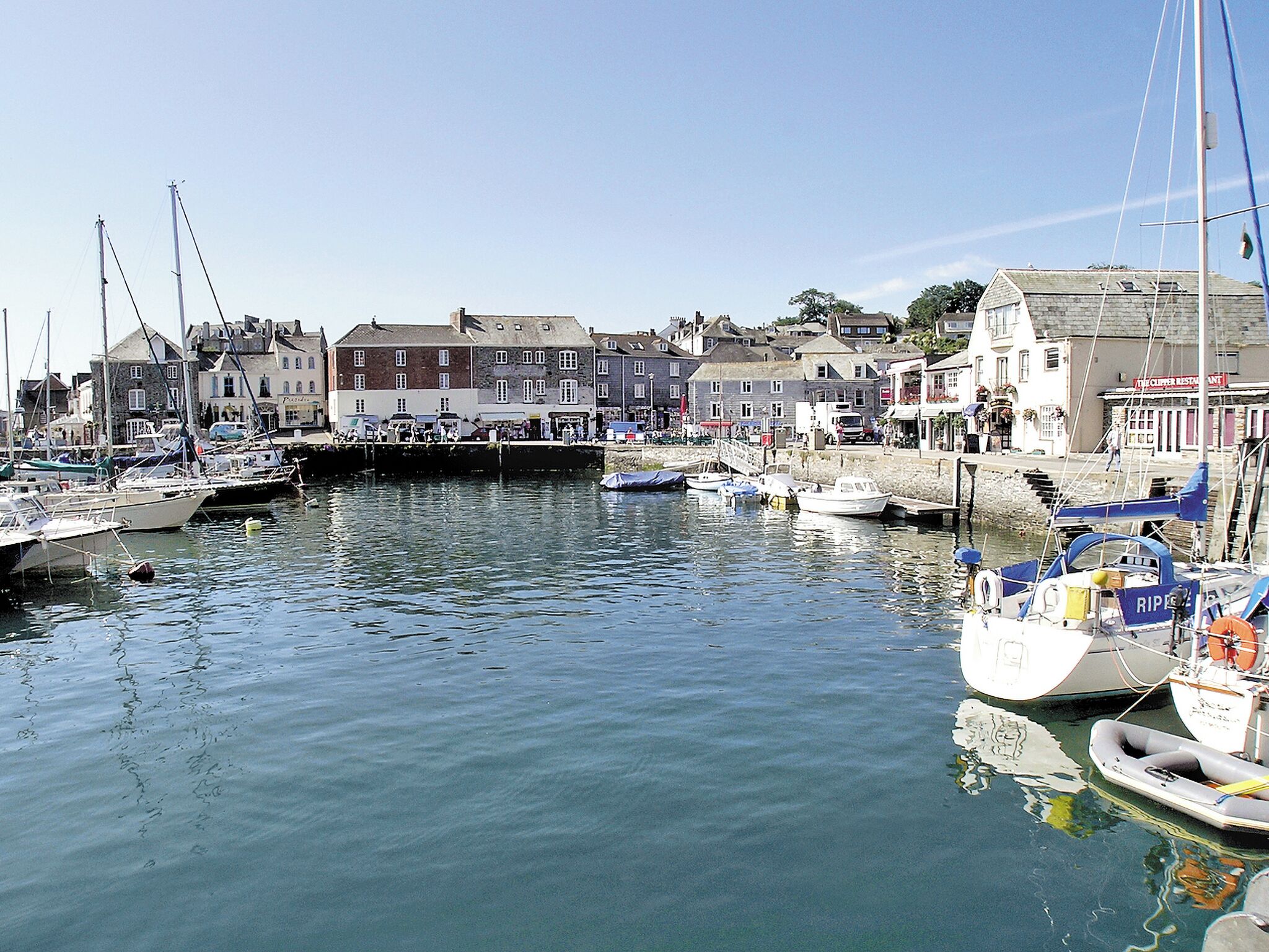 A harbor with boats docked, buildings along the waterfront, and a clear sky.