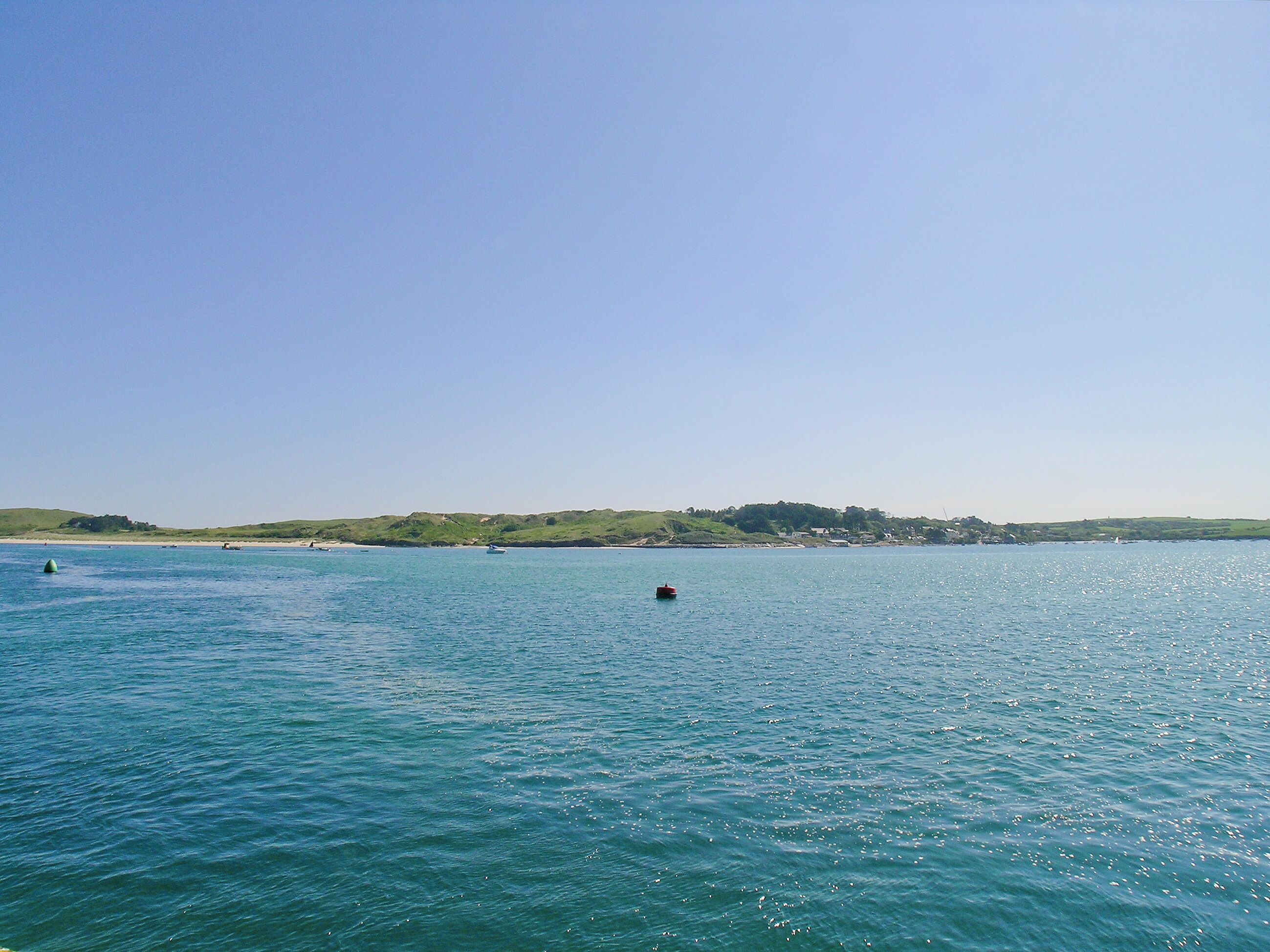 Une mer calme, avec des bateaux et une côte lointaine.
