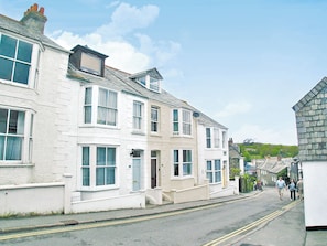 A street with white buildings, a clear sky, and a few pedestrians. - 3 bedroom accommodation in Padstow (Padstow)