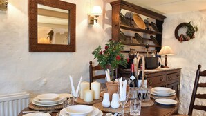 A dining table set with plates, candles, and a wine bottle, surrounded by chairs and a mirror.