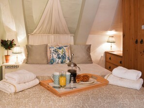 Un dormitorio con cama a dosel, lámparas de noche, una bandeja con alimentos para el desayuno y una planta en maceta.