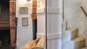 Une pièce avec une cheminée, un escalier et deux tableaux encadrés au mur.
