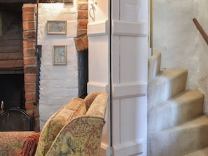 A room with a fireplace, a staircase, and a door with a sign.