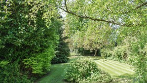 A well-maintained garden with a variety of shrubs and trees, a neatly trimmed lawn, and a clear pathway.