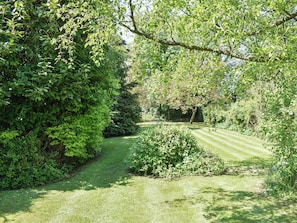 A well-maintained garden with a variety of shrubs and trees, a neatly trimmed lawn, and a clear pathway.