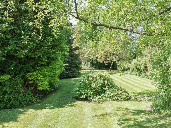 A well-maintained garden with a variety of shrubs and trees, a neatly trimmed lawn, and a clear pathway.