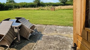 Une terrasse dotée de meubles en osier, avec une structure en briques en arrière-plan.