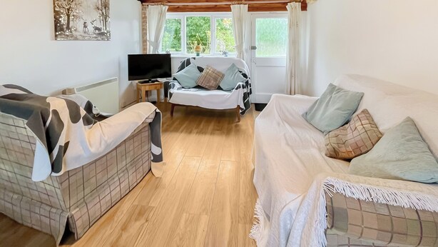 Une pièce confortable avec un lit, deux canapés, une télévision et une fenêtre avec des rideaux.