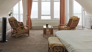 A room with a bed, two wicker chairs, a small table, and a TV. - 1 bedroom accommodation in Ramsgate (Ramsgate)