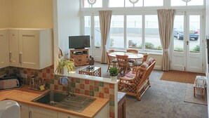A modern kitchen with a dining area, large windows with curtains, and a view of the street. - 1 bedroom accommodation in Ramsgate (Ramsgate)