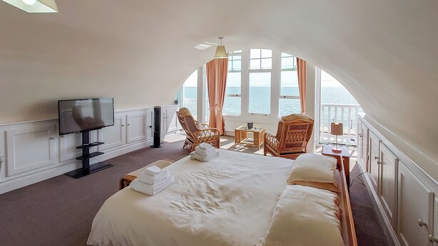 A bedroom with a large bed, a TV, and a view of the sea through large windows. - 1 bedroom accommodation in Ramsgate (Ramsgate)