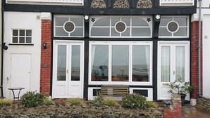 A two-story building with a white door, large windows, and a small balcony. - 1 bedroom accommodation in Ramsgate (Ramsgate)