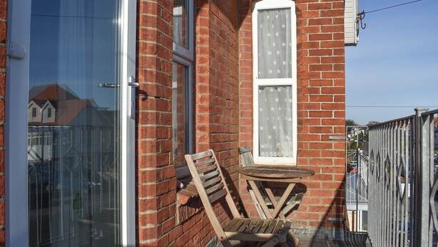 Una silla y una mesa de madera frente a un edificio de ladrillo con una ventana y una puerta.