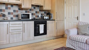 Una cocina compacta con armarios de madera, un microondas, una estufa y un tostador.