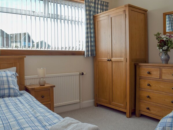 A bedroom with a bed, a nightstand, a wardrobe, and a dresser. - 3 bedroom accommodation in St Andrews (St Andrews)